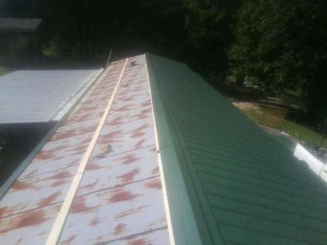 Old rusted panels beside newly installed green metal roofing — Wind Damage Roof Repair by Roofing Brothers in Buckland
