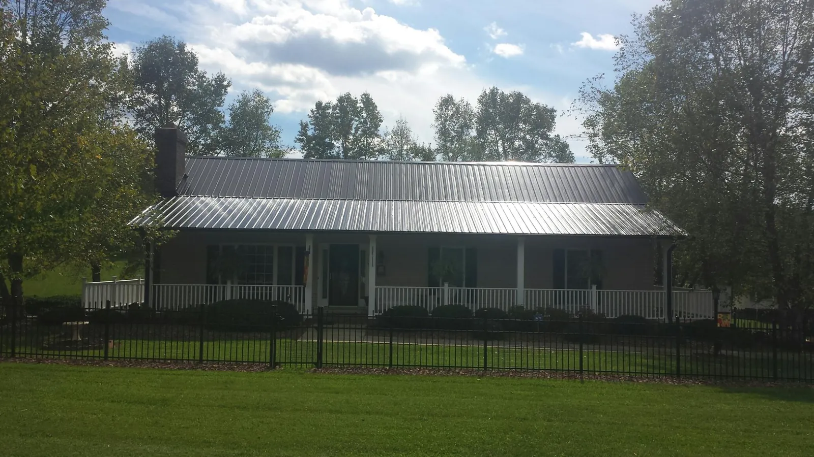 Gray metal roof on a brick ranch with a full width front porch — Gutter Guard Installation work by our crew in Buckland