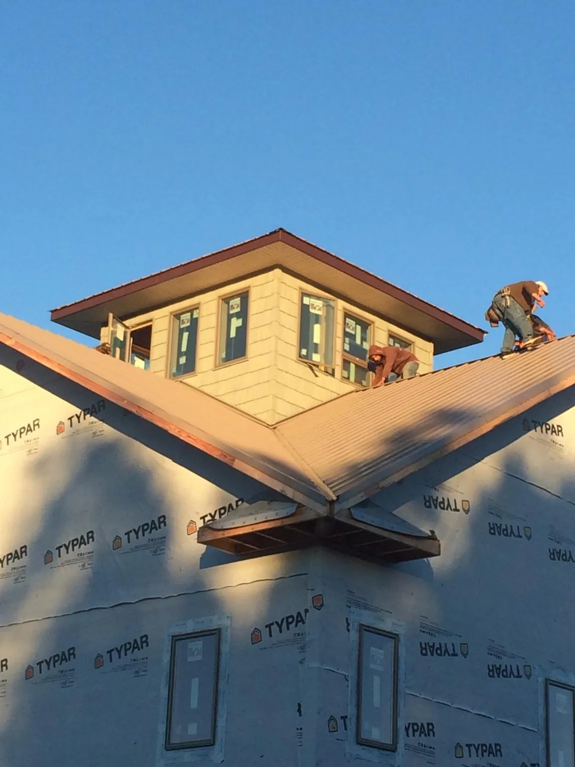 Roofers working around a rooftop cupola on a new metal roof at sunset — Roof Waterproofing in Buckland by Roofing Brothers